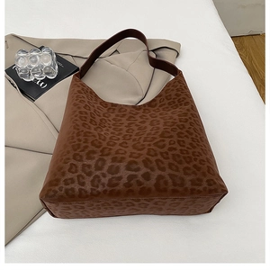 Sac hobo marron foncé imprimé léopard présenté sur un fond de trench-coat beige chic