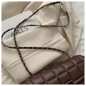 Détail du sac en cuir matelassé marron foncé avec chaîne en métal et boucle carrée