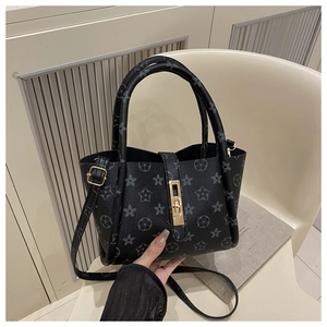 Detail of a black patterned leather tote bag with gold swivel lock and star print