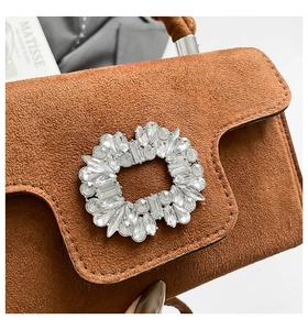 Detailed close-up of brown suede handbag with sparkling crystal rhinestone buckle and texture