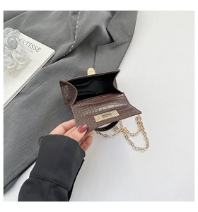 Detail of dark brown croc-effect mini bag with gold chain strap and magnetic flap