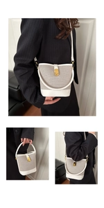 Close-up of contrast stitching on white leather and woven fabric bucket bag with gold lock