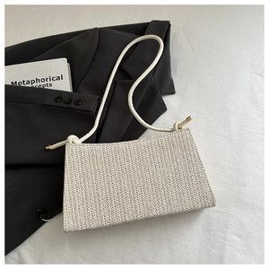 Detail of beige straw tote bag with herringbone weave and thin shoulder straps