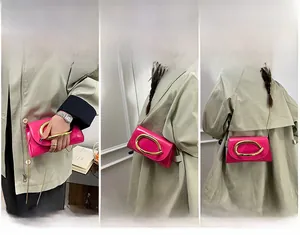 Detail of rose red patent leather crossbody bag with bold gold semi-circle handle