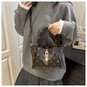 Detail of dark brown tote bag with classic star pattern and golden metal turn-lock closure