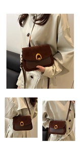 Detail of dark brown leather crossbody bag featuring gold horseshoe buckle and textured suede
