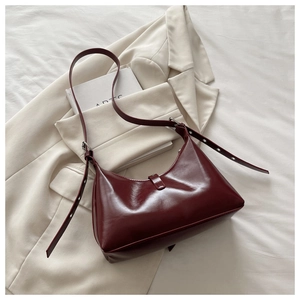 Gros plan d'un sac hobo en cuir verni bordeaux avec bandoulière réglable et boucle métal