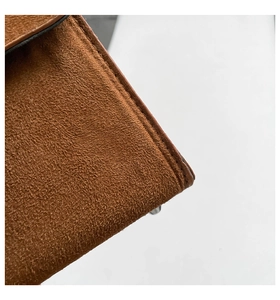 Detailed close-up of dark brown suede leather material with precise stitching on the edge