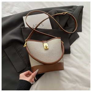 Close-up of contrast canvas bucket bag with leather trim and gold metal swivel lock