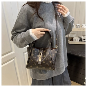Detail of vintage floral star monogram print and metallic lock on brown tote bag