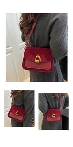 Detail of dark red crossbody bag showing suede splicing and golden horseshoe buckle