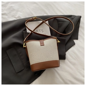 Detail of contrast bucket bag showing beige canvas and brown lychee grain leather textures