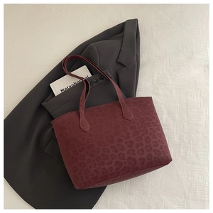 Close-up of leopard print tote bag in burgundy over a grey blazer for office style