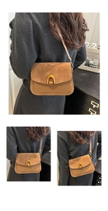 Detail of a brown leather crossbody bag featuring a golden horseshoe buckle and suede flap