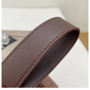 Détail macro d'une bandoulière en cuir marron foncé grainé avec coutures fines de sac porté épaule