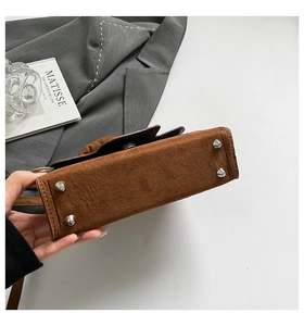 Detail view of brown suede bag bottom with silver protective metal rivets and fine stitching