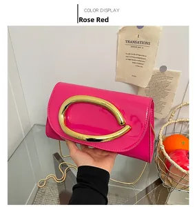Detail of fuchsia patent leather handbag with a large gold oval buckle and chain strap