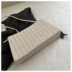 Detail of herringbone weave texture on a cream-colored minimalist crossbody bag