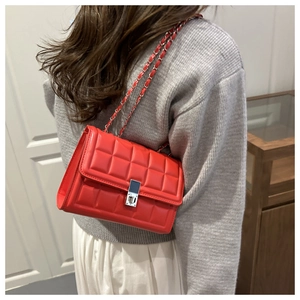 Detail of red quilted chain shoulder bag featuring silver-tone metal twist lock closure