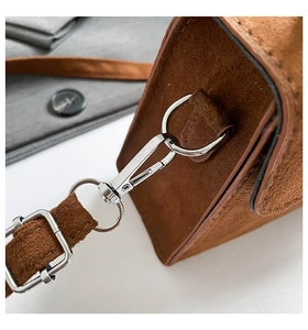 Detailed macro view of silver metal hardware and lobster clasp on brown suede handbag