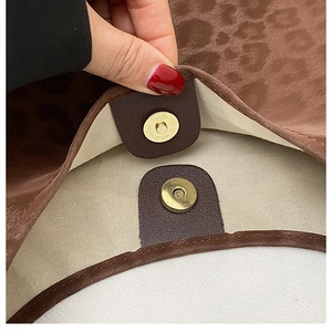 Détail de la boucle magnétique dorée sur sac à bandoulière en satin à motif léopard
