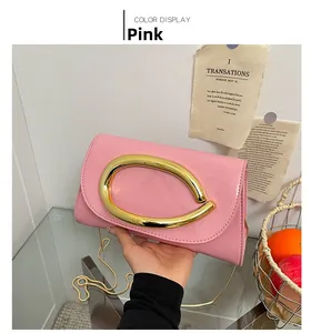 Detail of pink patent leather handbag featuring large gold metal oval buckle and chain strap