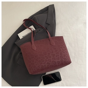 Detail of burgundy leopard print tote bag with long handles on a gray blazer background