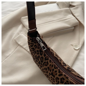 Close-up of leopard print bag texture with leather strap and silver metal zipper detail