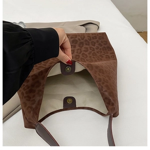 Detail view of the bronze magnetic snap closure and interior of leopard print tote bag