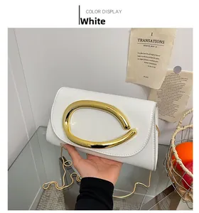 Detail of white evening clutch bag featuring a polished gold oval buckle and chain strap