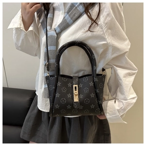 Detail of grey tote bag with star patterns and golden buckle worn by a model