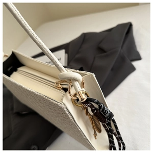 Detail of white woven texture shoulder bag with gold zipper and decorative charm