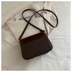 Detail of vintage brown crossbody saddle bag with suede flap and gold hardware accents