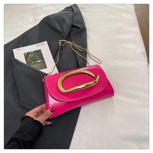 Detail of fuchsia patent leather bag featuring a large gold metal ring and chain strap