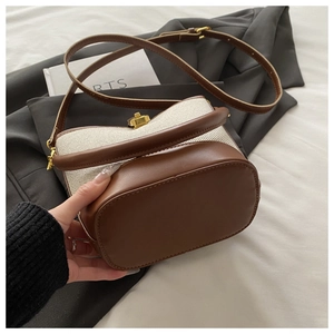 Detail of minimalist bucket bag showing beige canvas texture and brown leather trim