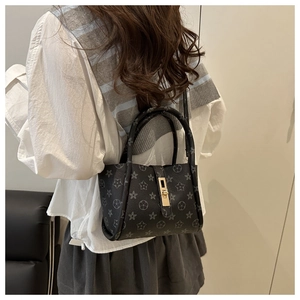 Detail of black mini handbag featuring vintage flower pattern and golden metal lock