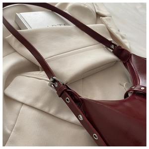 Détail du sac en cuir bordeaux montrant la boucle argentée et la sangle rivetée
