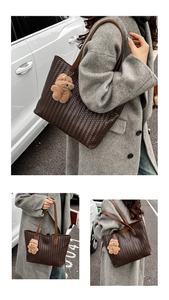 Detail of dark brown woven tote bag featuring a plush bear charm and thin shoulder straps