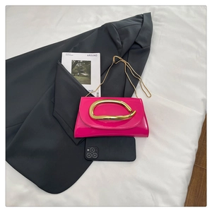 Detail of hot pink patent leather bag with unique gold wavy handle and chain strap