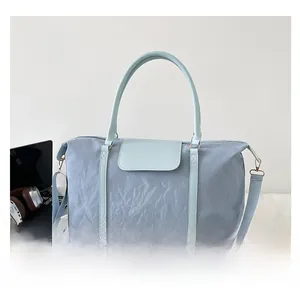 Close-up of light blue travel duffel bag with crinkle nylon texture and shoulder strap