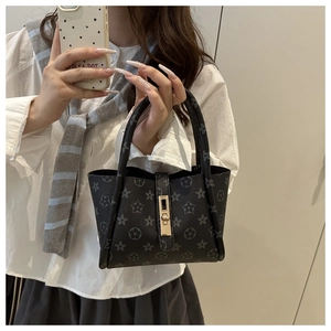 Detail of grey star print tote bag with golden rotating lock and double handles