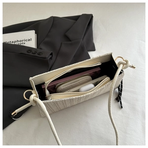 Detail view of woven shoulder bag interior storage showing phone, wallet and accessories