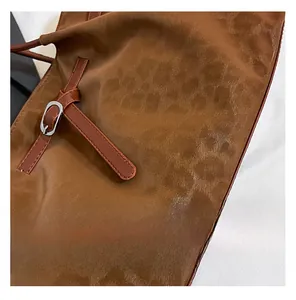 Detailed close-up of brown tote bag with leopard texture and silver metallic buckle
