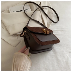 Detail of a dark coffee crossbody bag with a gold buckle and premium suede texture