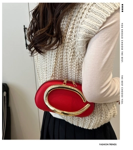 Detail of red pebbled leather semi-circle bag with golden C-logo and chain strap