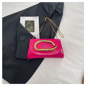 Detail of fuchsia patent leather handbag with gold streamlined metal handle and chain strap