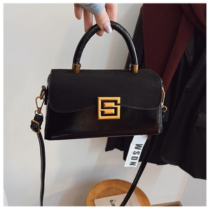 Detail of black crossbody bag featuring mixed texture leather and golden square buckle