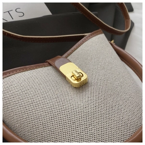 Detailed macro of vintage beige canvas bag featuring brown leather trim and gold metal clasp