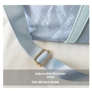 Detail of adjustable blue fabric strap with golden metal buckle on a travel bag