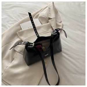 Détail d'un sac baguette en cuir PU noir brillant avec boucle argentée sur un blazer